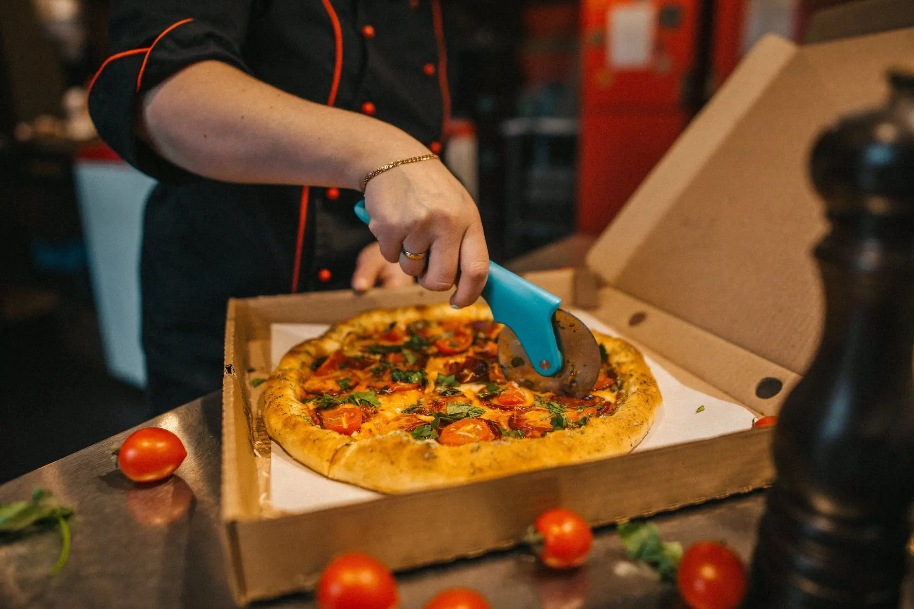 person cutting pizza with a pizza cutter